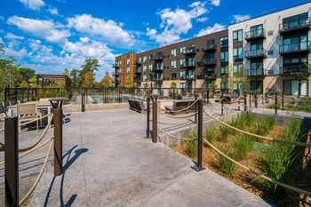 an open area with benches and rope barriers in front of an apartment building